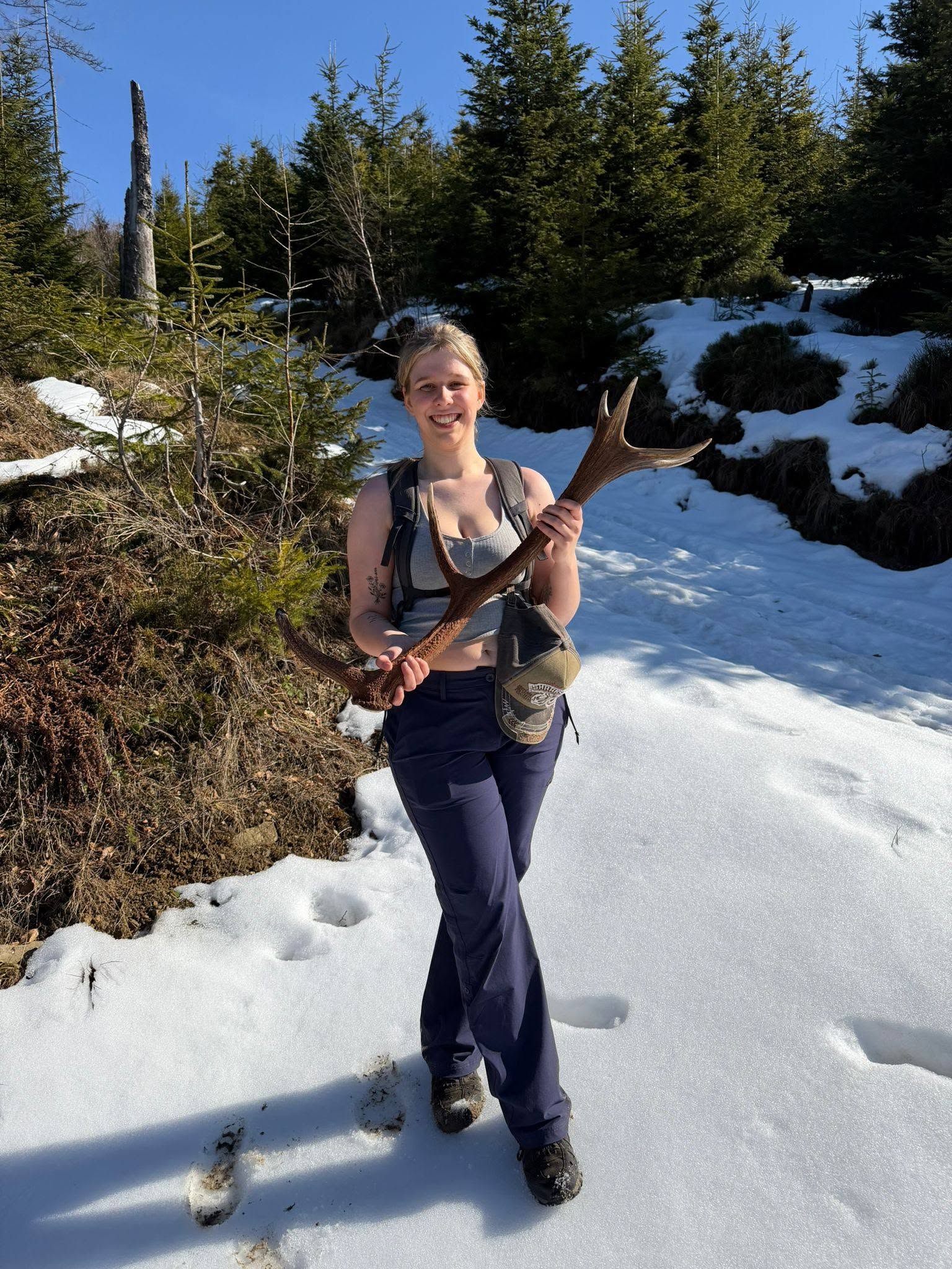 Student standing in the snow and holding a stag antler on an international field trip