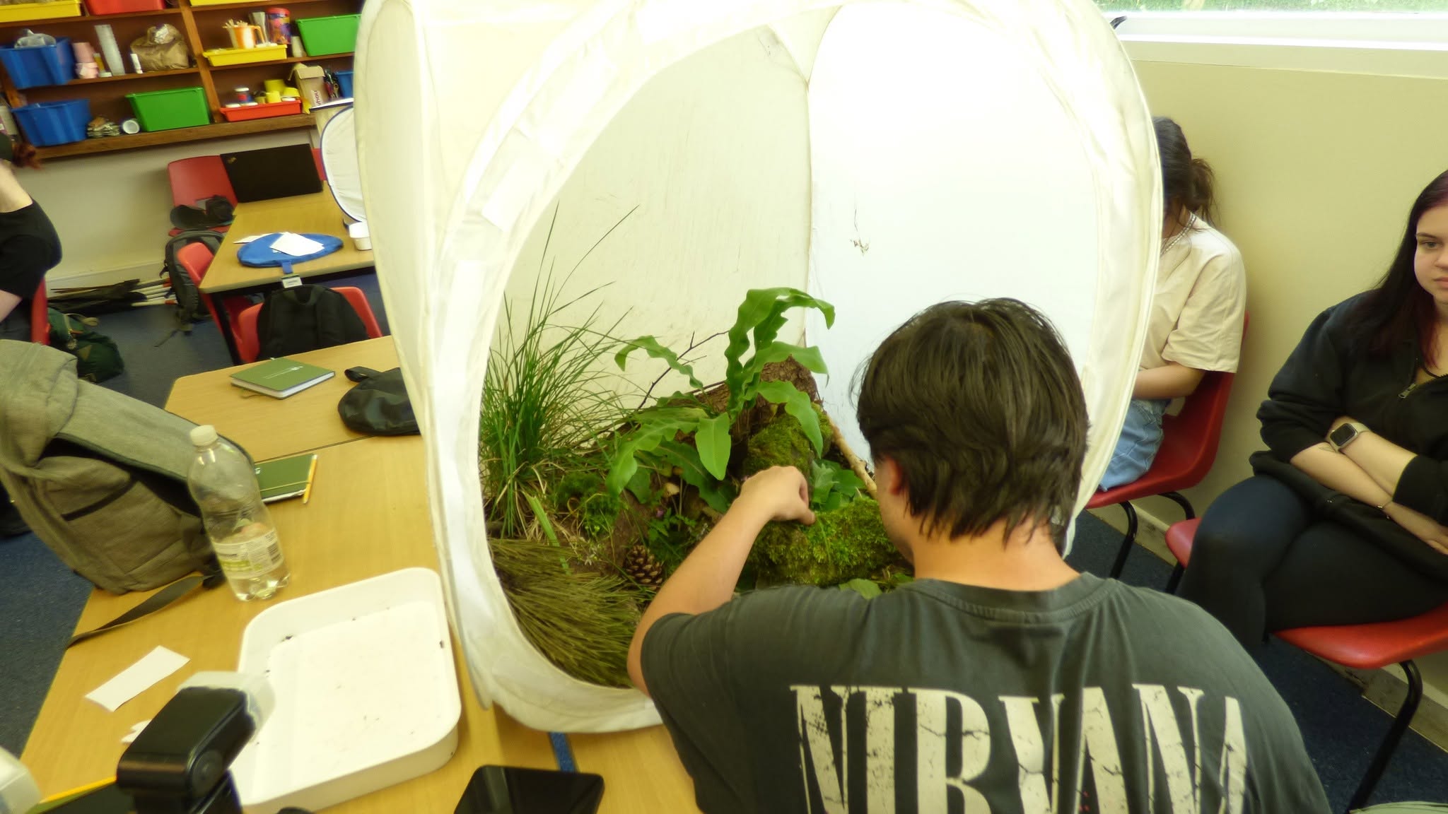student in classroom working on some grass and plant life inside a tent.