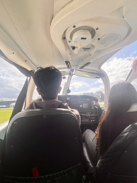 Two aerospace students are sat in the cockpit of a small aircraft.