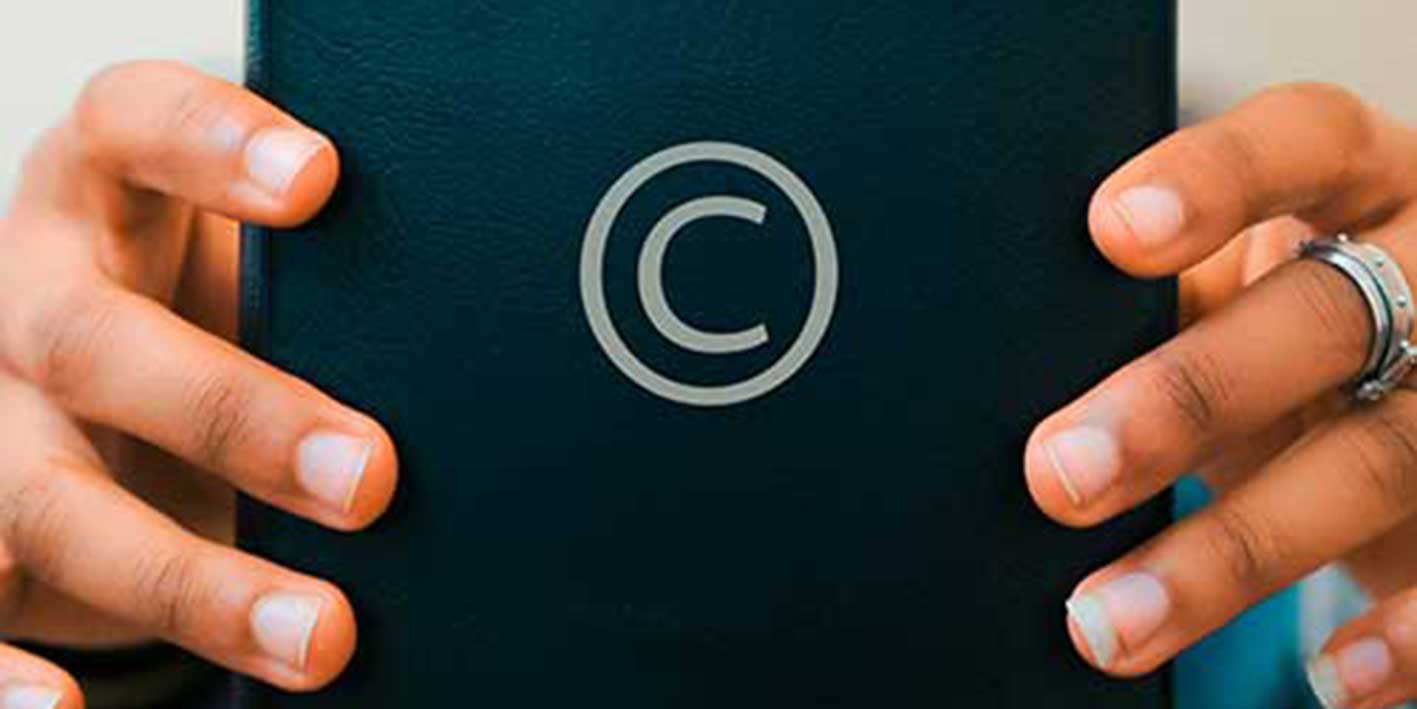 Image of a person holding a book with the copyright symbol on the cover
