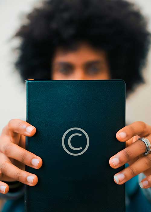 A man holding a book in front of him with the copyright symbol displayed on the cover.