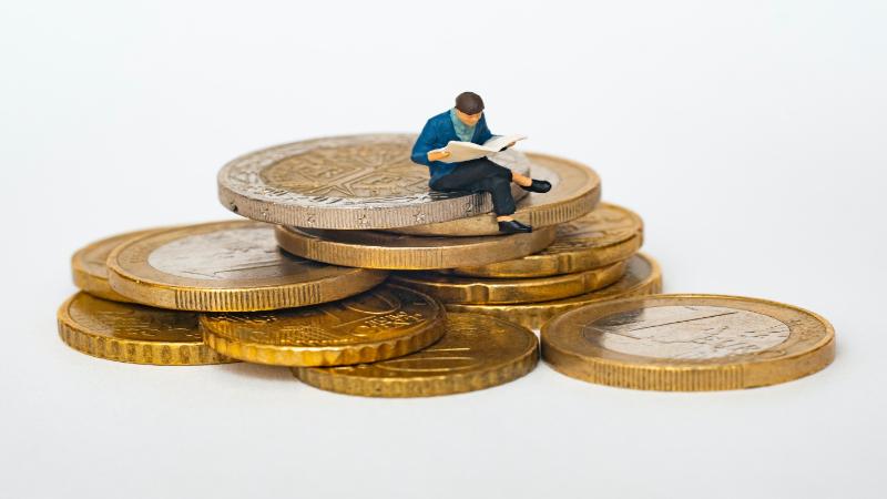 A man reading while sitting on a pile of coins