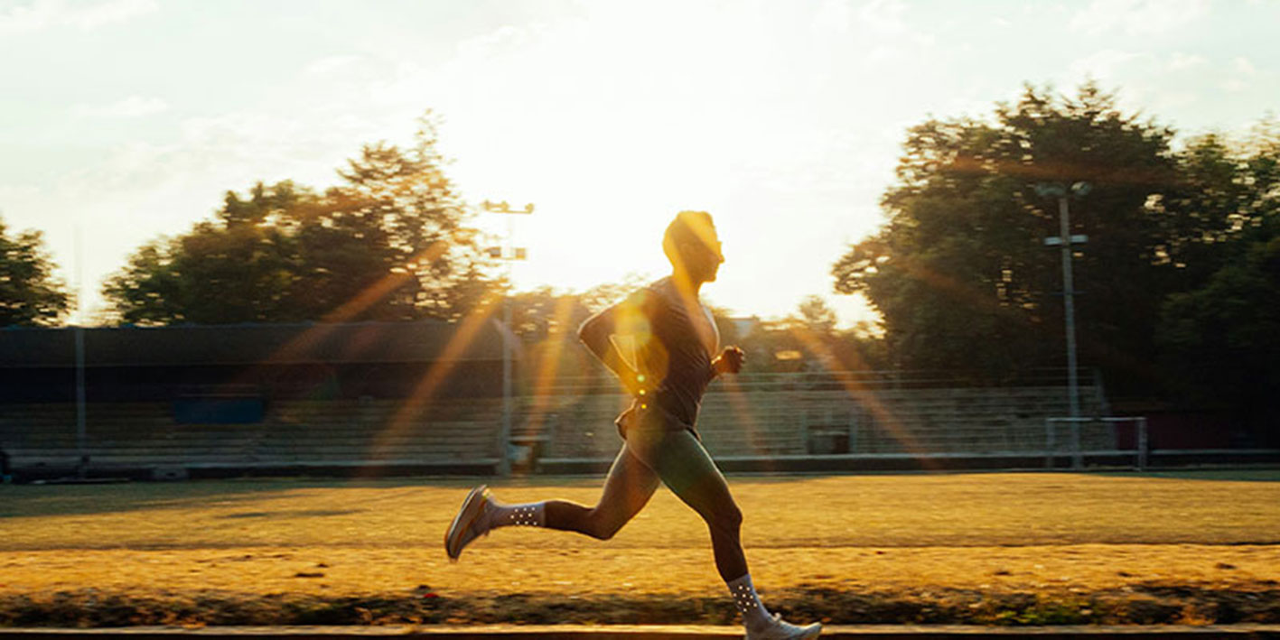 a man running in a park as the sun is setting