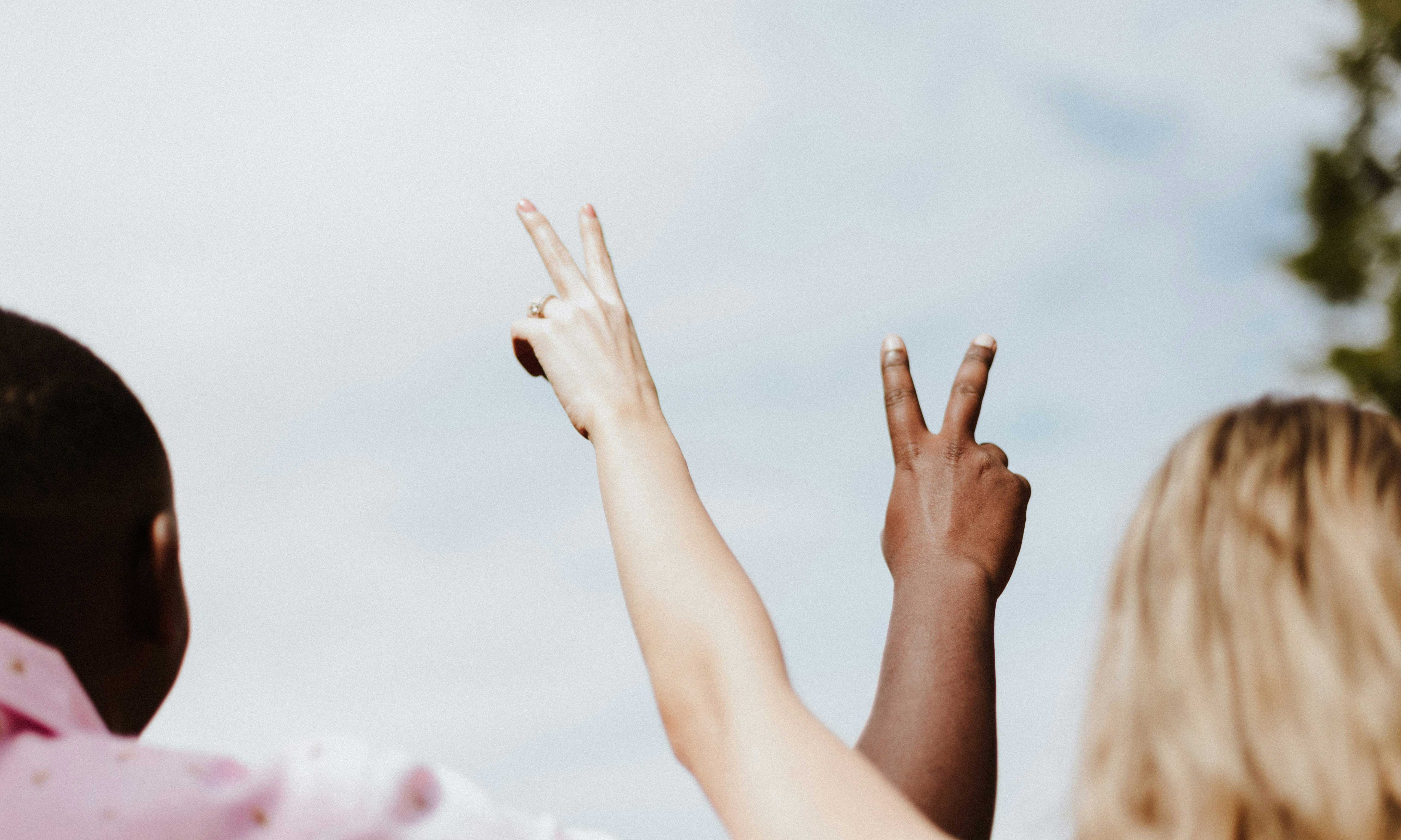 two people with their arms raised with fingers in a v sign