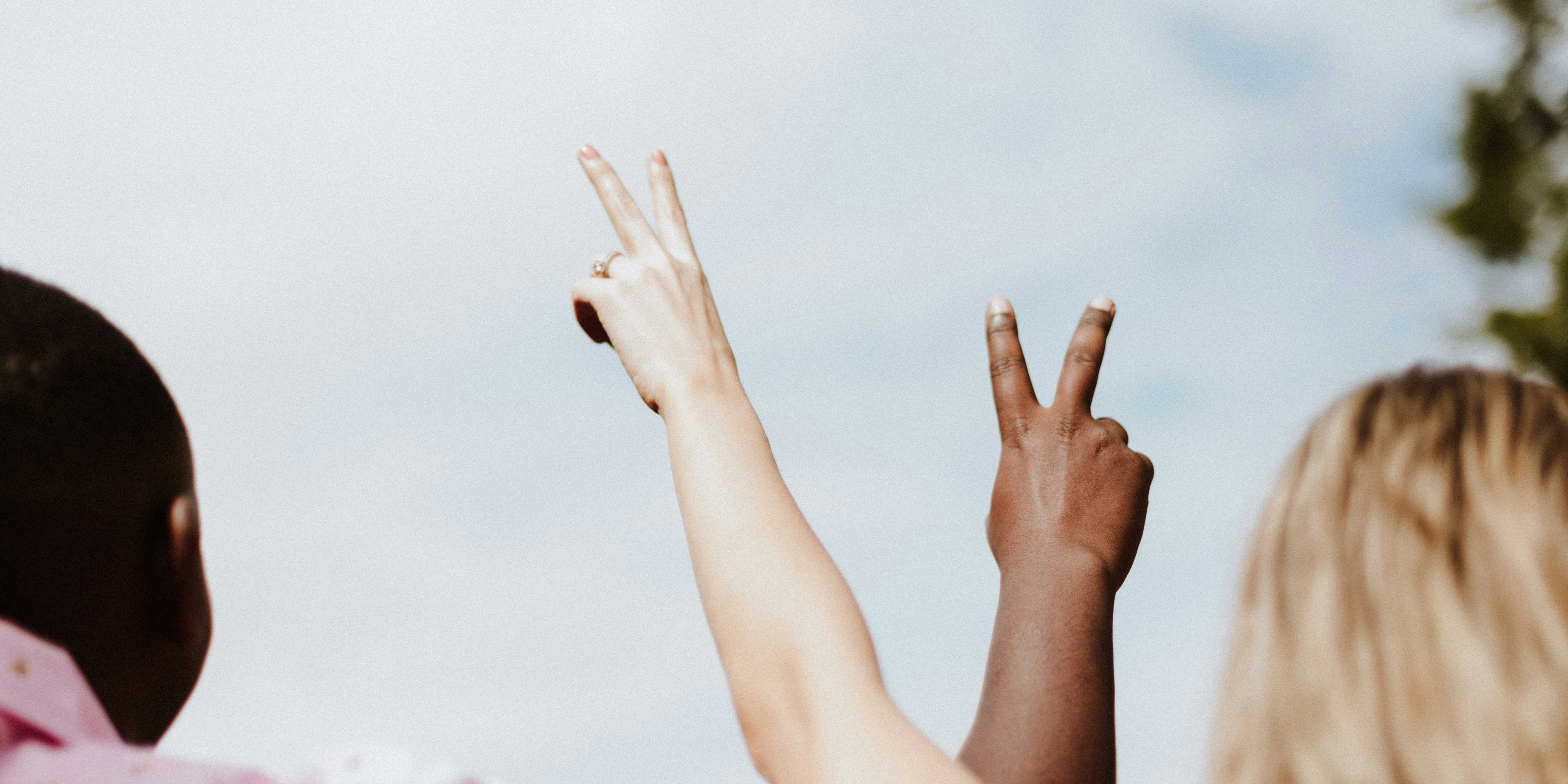 two people with their arms raised with fingers in a v sign