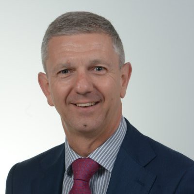 Alan Edwards photographed against a white backdrop wearing a suit.