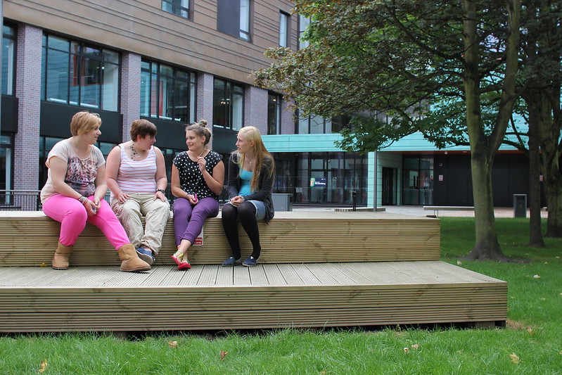 Students sitting outside together at Walsall Campus, talking among themselves