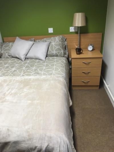Image of a 3/4 size bed in Telford accommodation, also showing a bedside table with a lamp