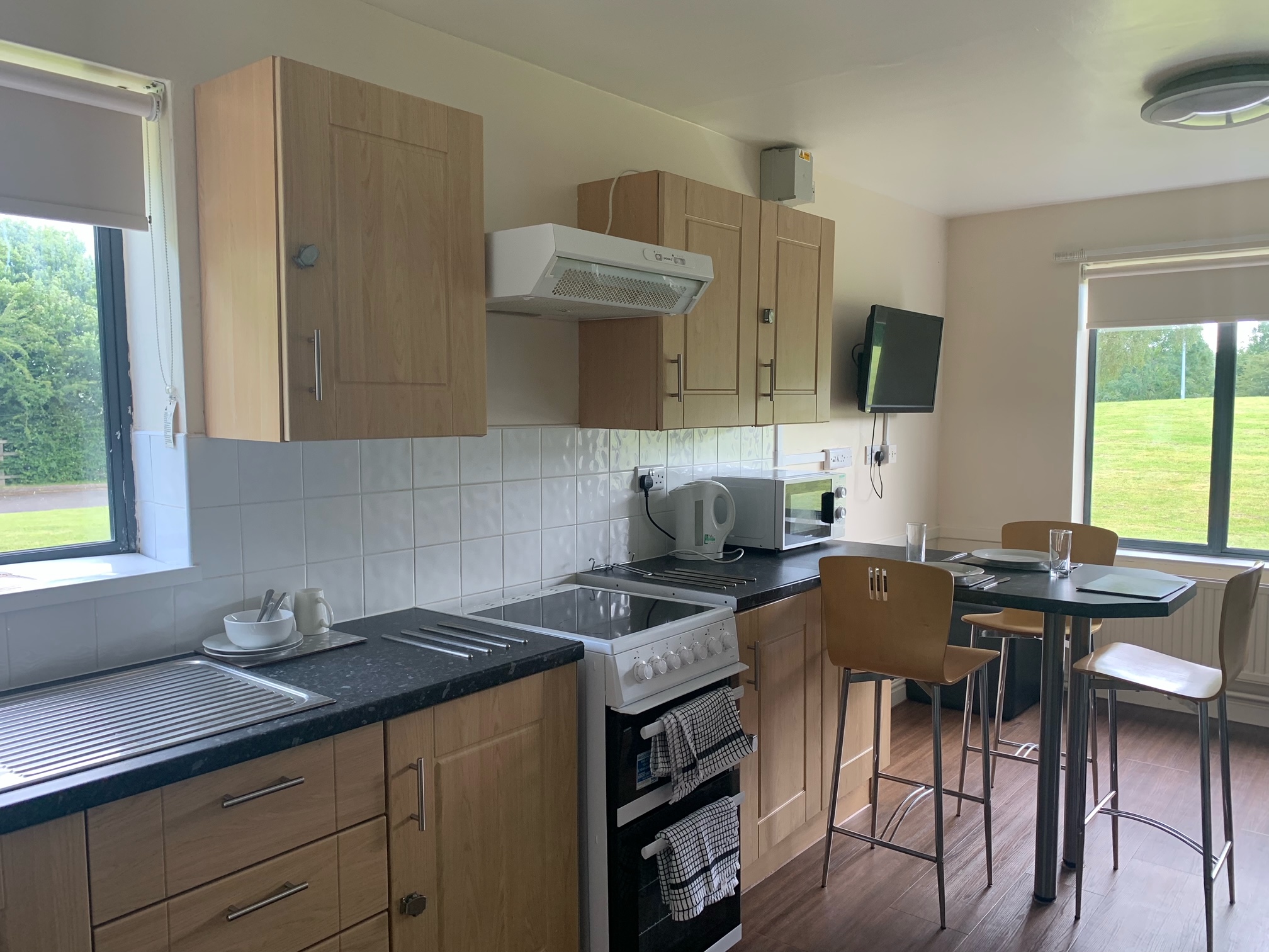 Kitchen in Telford Campus accommodation, with a table attached to a long countertop, a kettle and microwave, cupboards, drawers, an oven and a hob