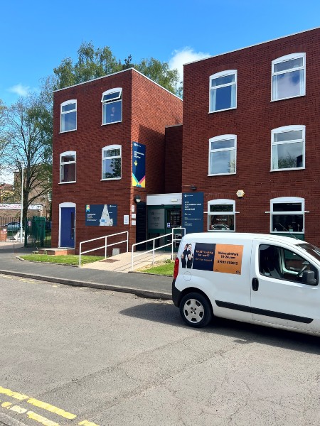 Exterior of the Accommodation Hub, a building with three floors and windows on each floor, signage identifying the building as the accommodation hub.