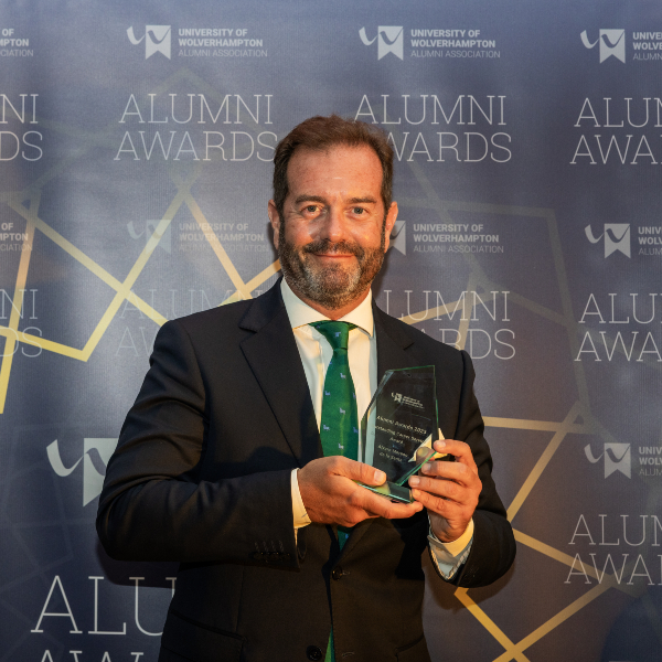 Alvaro Moreno de la Santa holding the honorary Outstanding Career Service Award at the Alumni Awards 2023 ceremony.