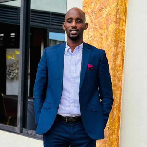 Arnold Kakama standing outside a building in a blue suit.