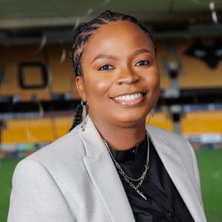 Bisola Olatunji standing in the Wolverhampton Molineux Stadium, wearing a white blazer.