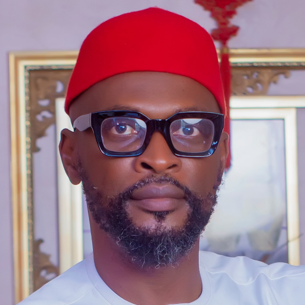 Chima Kalu standing in front of a framed painting.