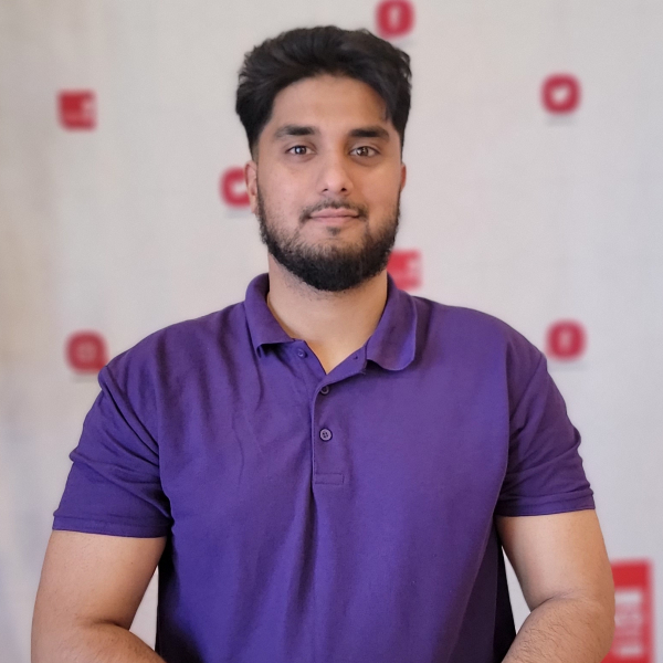 Faizaan Ali in a blue shirt posed against a white backdrop.