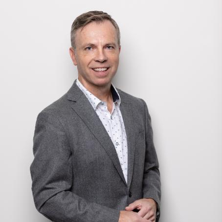 Graham Turner in a white studio wearing a grey suit.