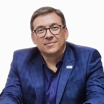 Marcel Botelho on a white background wearing a blue shirt and blazer.