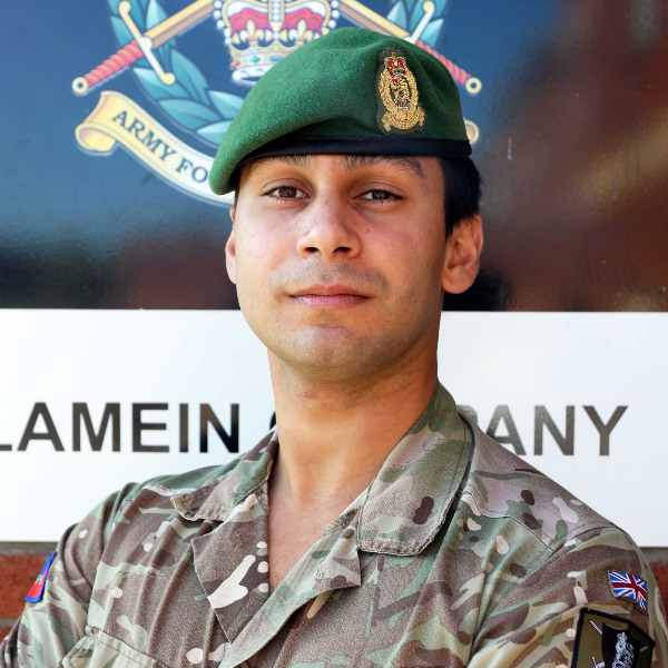 Mikhail Smethurst in military fatigues posing in front of a wall.