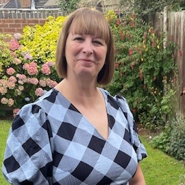 Sarah Crowshaw wearing a black-and-white checked outfit and standing in a garden.