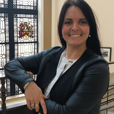 Profile photo of University of Wolverhampton alum Clare Dickens. Clare is smiling and wearing a white top with a navy jacket.