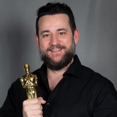 Profile photo of University of Wolverhampton alum Manolo Mantero. Manolo is wearing a black shirt, and is holding an Oscar statue.