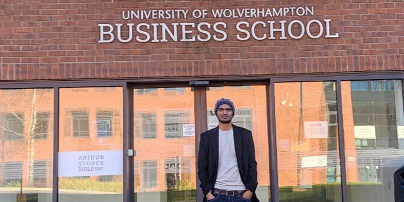 Student standing outside the University's Business School