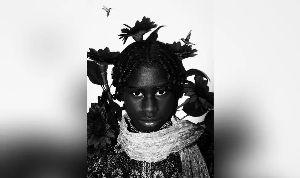 A portrait of a young black woman staring into the camera