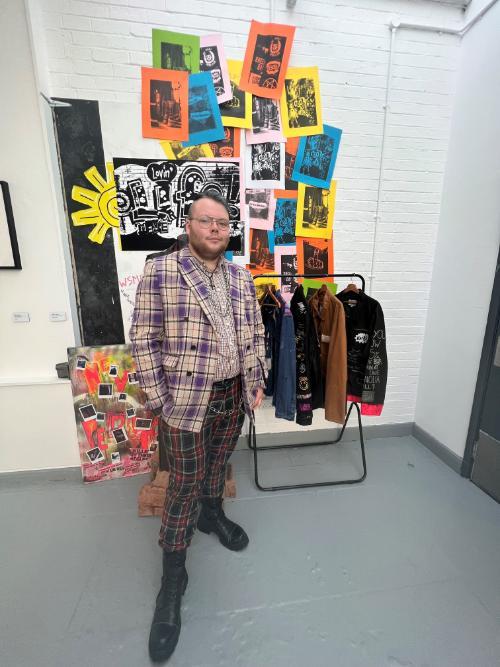 Student posing in front of his work at the annual Degree Show