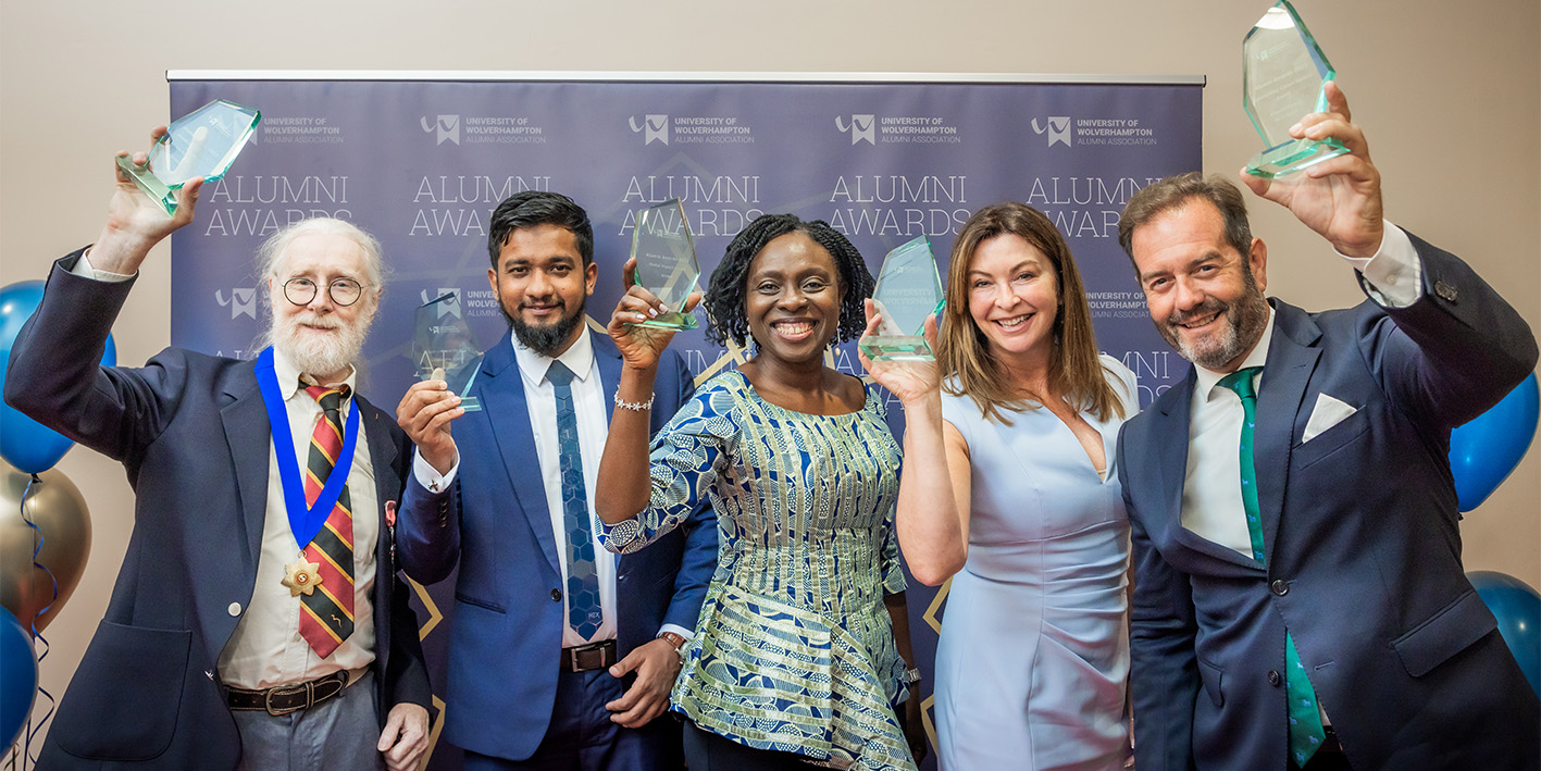 group photo of winners of the 2023 Alumni Awards holding up trophies