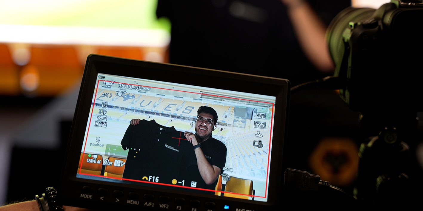 An image of a potential student holding up a Wolves Uni shirt in a football club