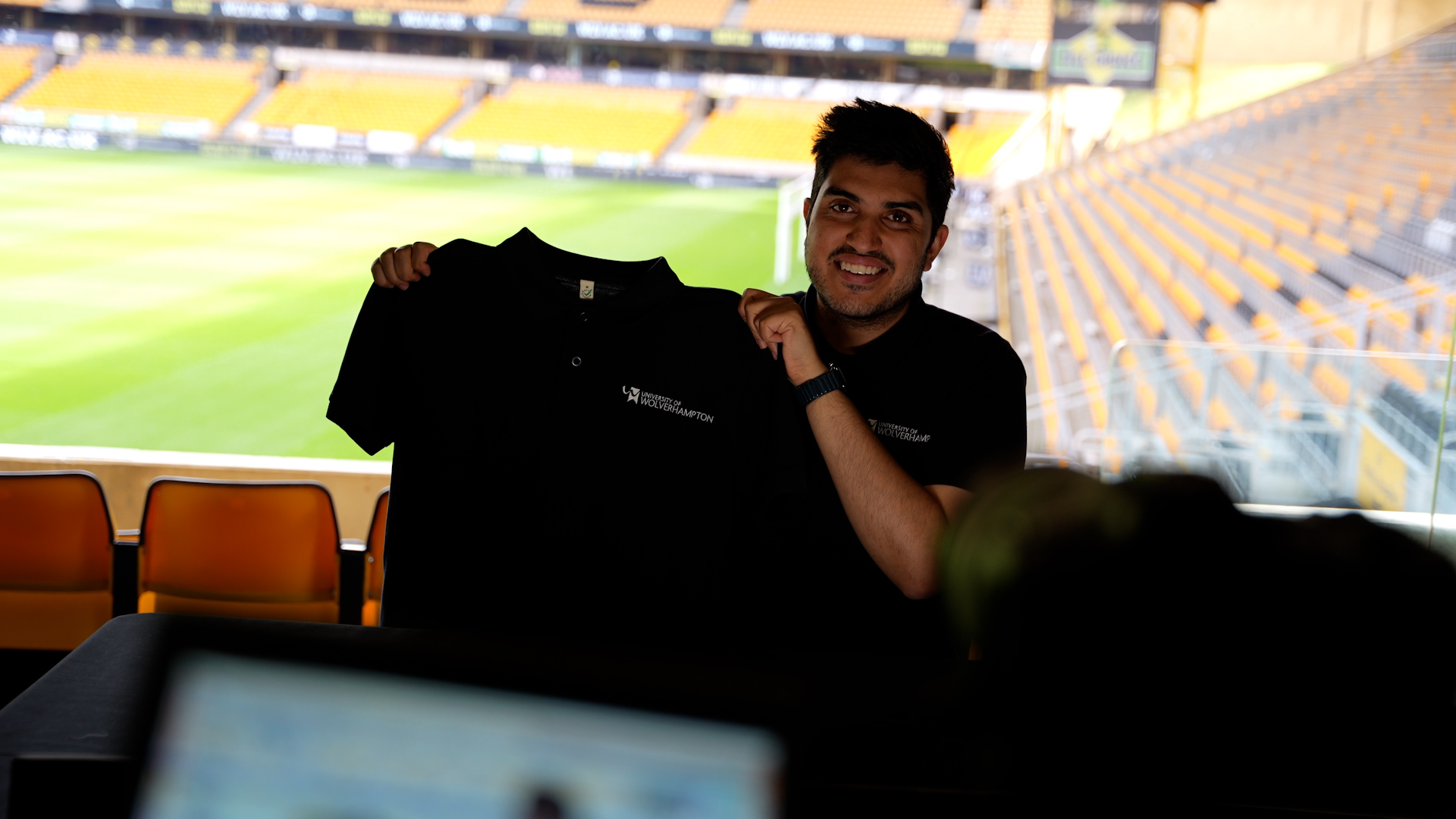 An image of a potential student holding up a Wolves Uni shirt in a football club