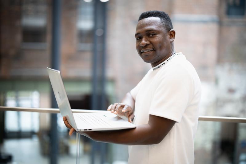 Portrait of Julius Odede holding a computer
