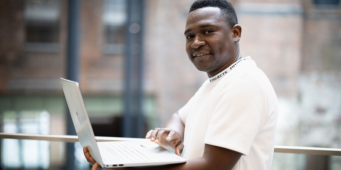 Portrait of Julius Odede holding a computer
