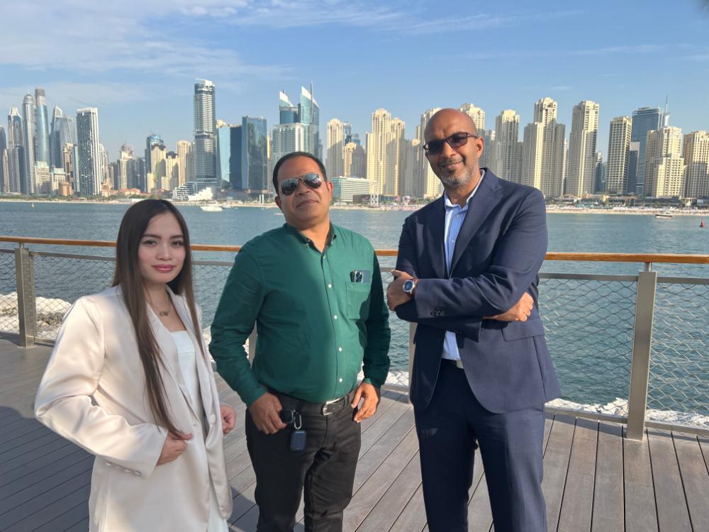 Three notable alumni in Dubai looking at the camera with the skyline behind them