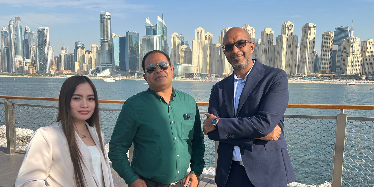 Three notable alumni in Dubai looking at the camera with the skyline behind them