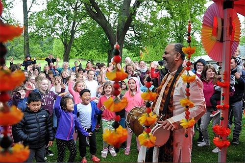 Peter Chand performing with drum in front of a crowd of children and families