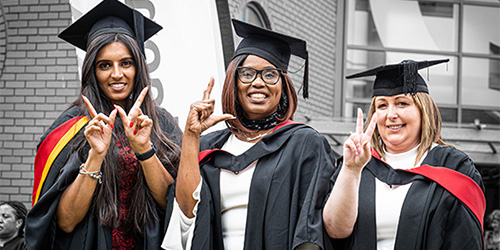 three robed graduates at Graduation Ceremony