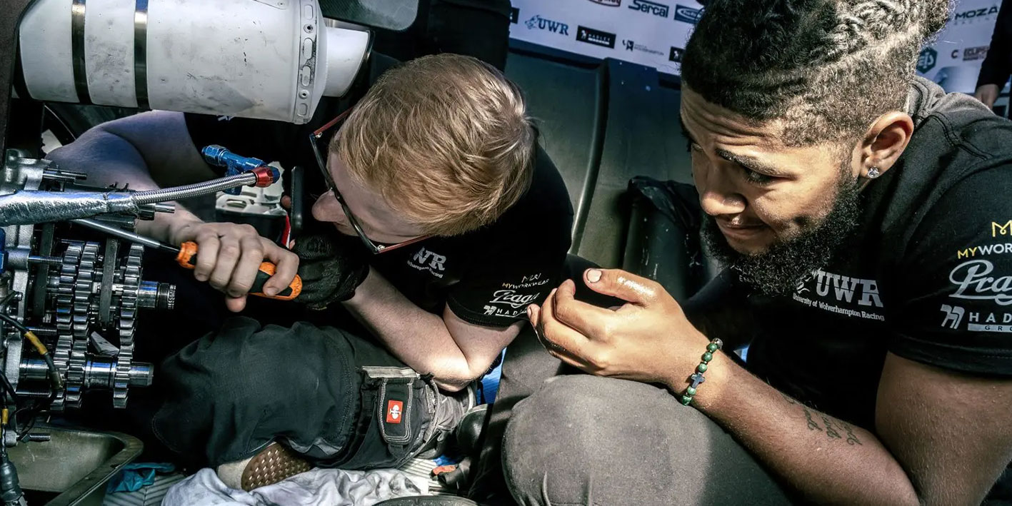 An image of two Motorsport students engineering a race car