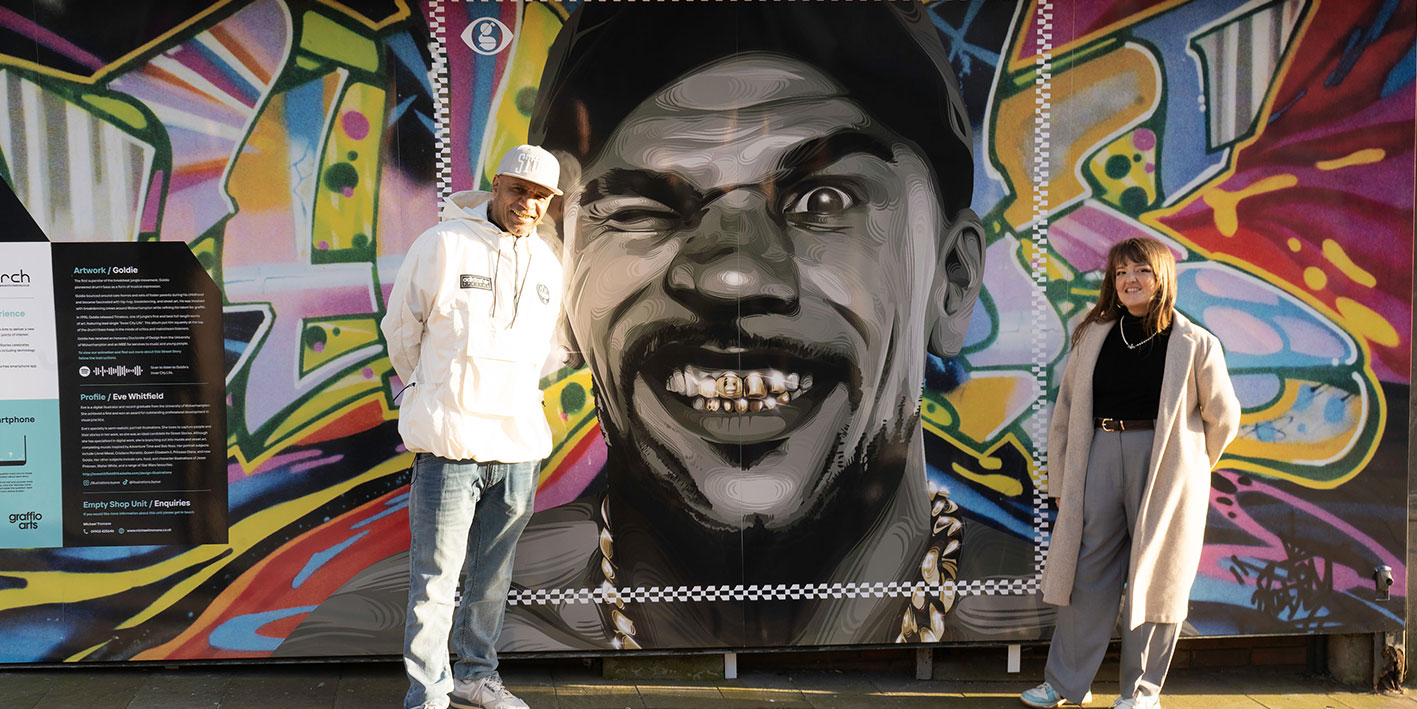 Image of Goldie standing in front of a mural created by Illustration student
