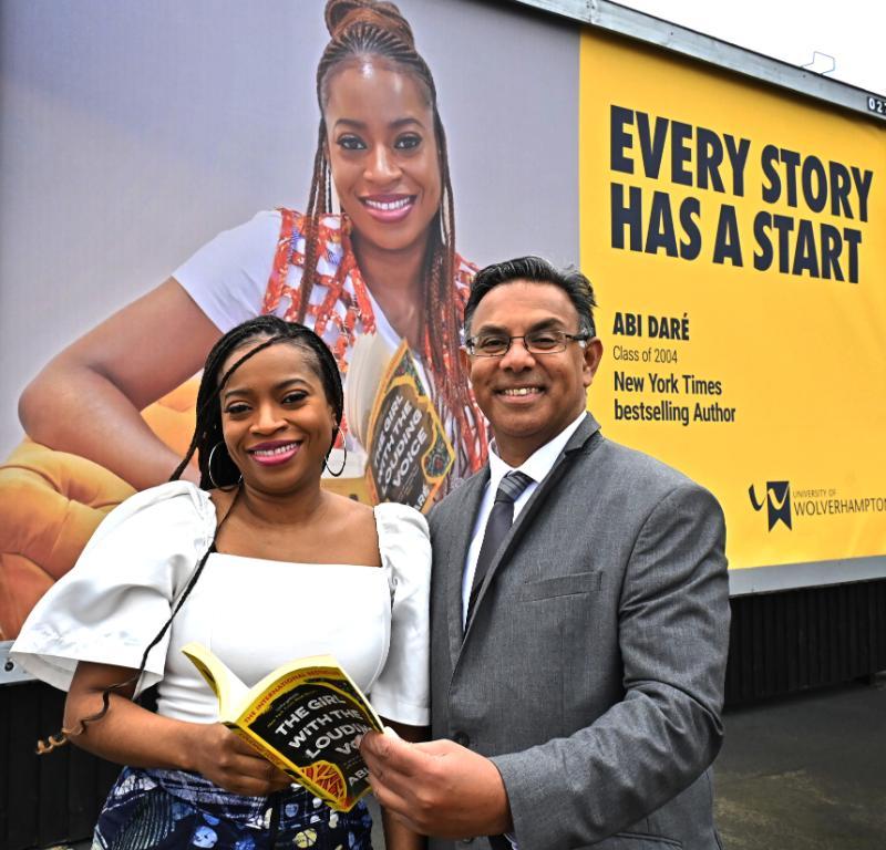 A picture of alumna Abi Dare and the Vice Chancellor in front of her billboard