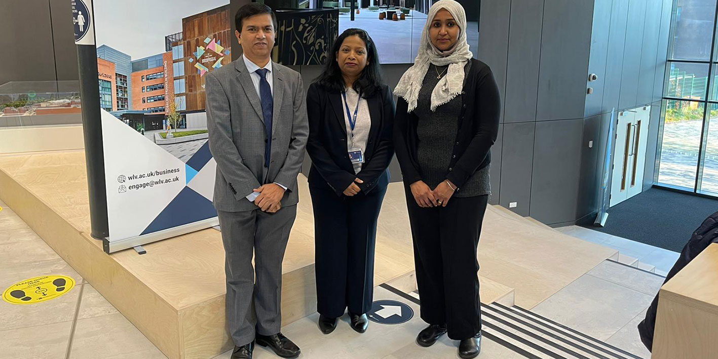 Three academic researchers stand in front of a promotional zap stand