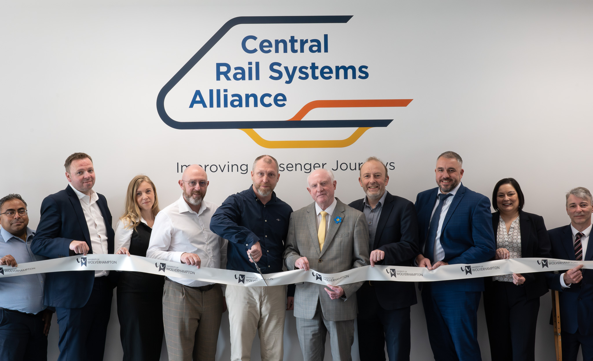 A group of people cutting a ribbon for a room sponsorship
