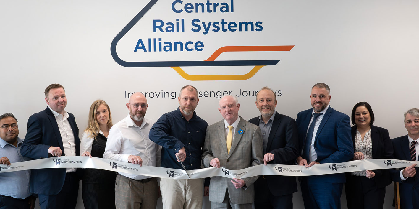 A group of people cutting a ribbon for a room sponsorship