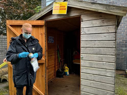 A student standing outside a shed mock up of a crime scene