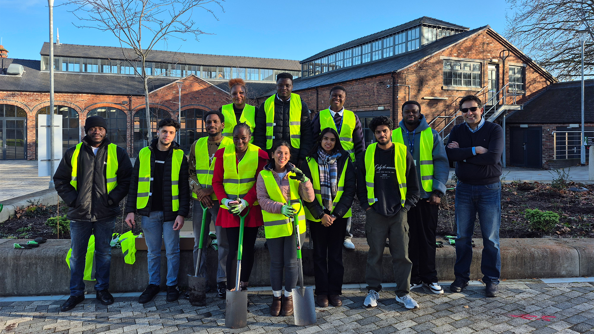 Architecture students and academics with Estates team members wearing hi-vis vests gather for a group photo at Springfield Campus