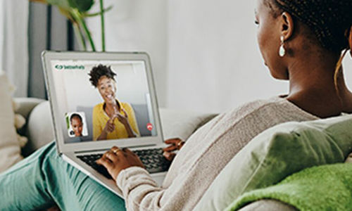 woman on sofa engaging in online therapy through a laptop
