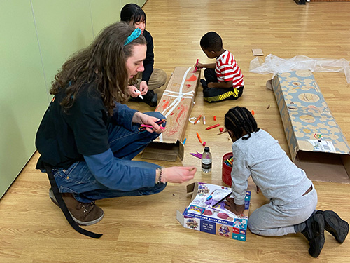 student volunteer play working with children on the floor