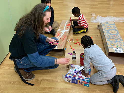 student volunteer play working with children on the floor