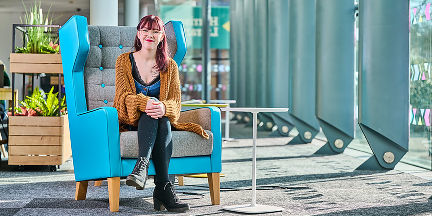 Student sitting in high back chair in the refurbished Harrison Library
