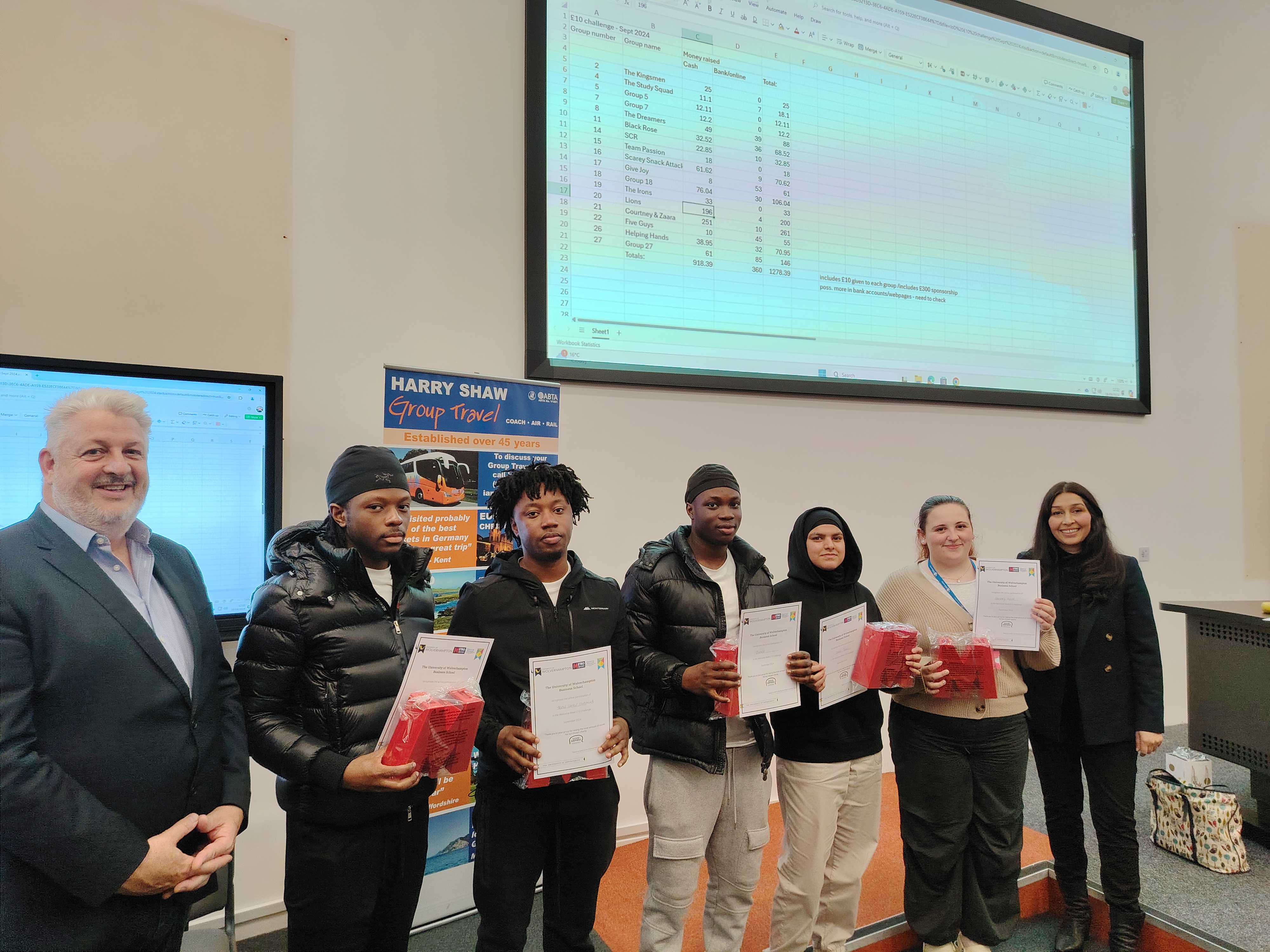 A group of students standing at the front of a lecture theatre with certificates